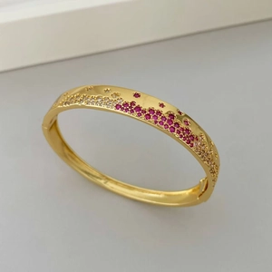 Détail du bracelet doré serti de pierres rouges et blanches avec fermoir de haute qualité