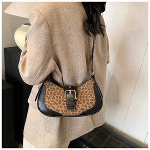 Détail du sac à bandoulière léopard avec garniture en cuir noir porté par un modèle