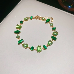 Close-up of gold chain bracelet with various green zircon gemstones and extension link