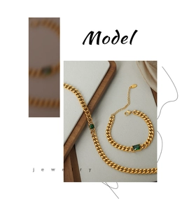 Close-up of gold Cuban chain set with emerald green stones on stone background