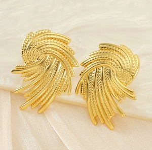Detail of golden geometric fan earrings with textured and smooth linear wing pattern