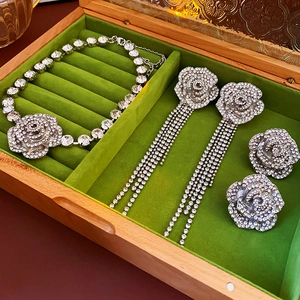 Gros plan d'un ensemble collier et boucles d'oreilles fleur argenté sur velours vert