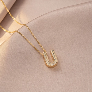 Macro shot of gold-plated letter U necklace pendant with sparkling zircon inlays