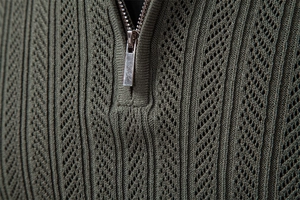 Detailed close-up of dark green knitted sweater featuring a premium silver metal zipper