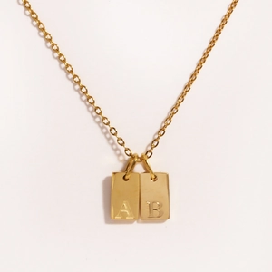 Detail of 18k gold plated square alphabet pendants with engraved letters A and B