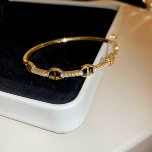 Macro shot of gold-plated oval bangle with CD logo structure and cubic zirconia pavé