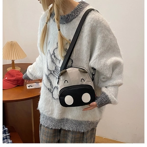 Mini canvas crossbody bag featuring a cute cartoon cow face on a beige background
