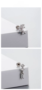 Macro detail of silver titanium steel earrings with zircons and pearls on white block
