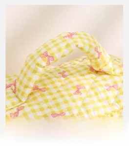Detailed shot of quilted yellow plaid fabric with pink bow prints and soft padded handle