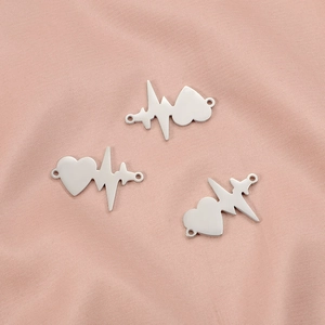 Polished silver stainless steel EKG heartbeat heart connectors on pink fabric background