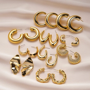 Detail of diverse gold geometric earrings on elegant champagne silk background