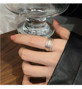 Detail of minimalist multi-layer silver ring on finger holding a glass cup