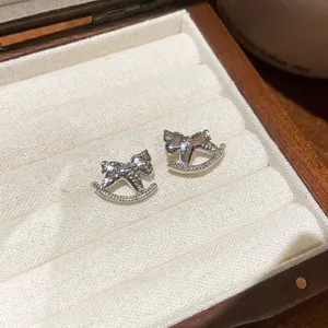 Boucles d'oreilles cheval à bascule en argent avec zircons dans un coffret cadeau en bois