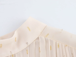Detail of elegant beige chiffon dress featuring metallic embroidery and pleated collar