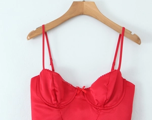 Detail of red satin corset top with delicate bow decoration and adjustable thin straps