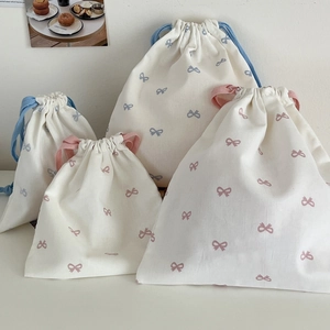 Close-up of cream canvas drawstring bags with pink and blue bow prints in various sizes