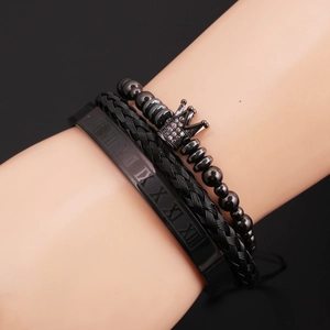 Detailed view of black beaded crown bracelet, leather braid, and Roman numeral bangle