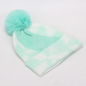 Detail of mint green and white tie-dye knit beanie with a large matching faux fur pompom
