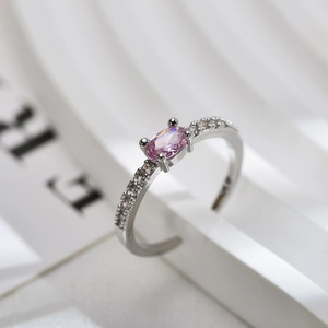 Macro view of a silver ring with an oval pink gemstone and small white zircons