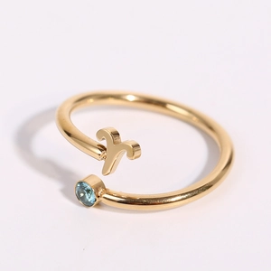 Detailed close-up of gold Aries zodiac ring with a sparkling blue round gemstone