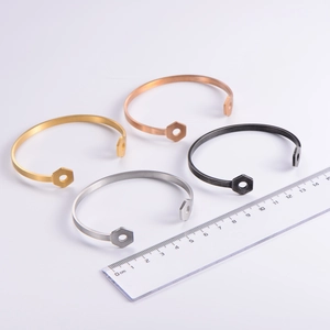 Macro detail of four-color brushed metal hex nut bracelets showing size on ruler