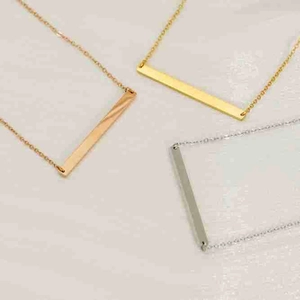 Detailed close-up of bar pendants in gold, silver, and rose gold on fine metal chains