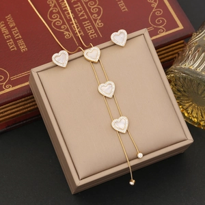 Detailed view of a gold heart jewelry set with inlaid white stones and pavé crystals