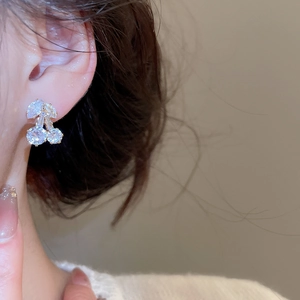 Close-up of model wearing silver cherry zircon stud earrings with sparkling clear crystals