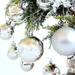 Silver Christmas tree ornaments in shiny and matte finishes hanging on snowy pine branches