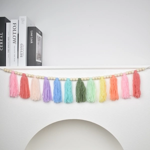 Detail of bohemian wood bead garland with colorful cotton tassels on a white mantel