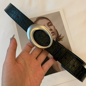 Détail de ceinture en cuir noir embossé crocodile avec boucle ovale argentée mate