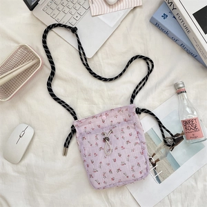 Flat lay detail of a purple floral canvas crossbody bag with drawstring closure and soft texture