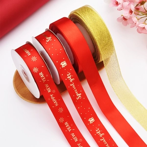 Detail of red and gold Christmas ribbons featuring Happy New Year gold foil printing