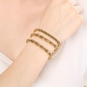 Close-up of triple layered gold cuban link bracelets on a model's wrist with 18k gold finish