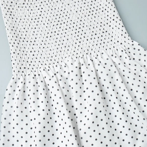 Detailed view of the smocking craft and black polka dot pattern on summer dress fabric