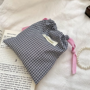 Close-up of black and white plaid drawstring bag with pink cords and woven label detail