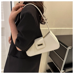 Detail of ivory faux leather shoulder bag with textured gold metallic buckle on black blazer