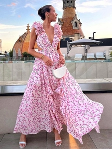 Elegante abito lungo a fiori rosa con scollo a V e volant su una terrazza al tramonto
