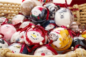 Detail of Christmas coral fleece socks in transparent bauble gift packaging with red ribbons