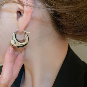 Close-up of a silver-toned chunky C-shape hoop earring worn on a model's ear