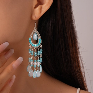Close-up of bohemian silver drop earrings with blue rhinestones and beaded tassels