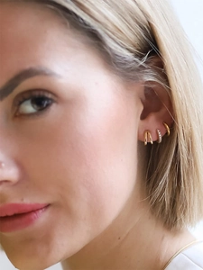 Close-up of gold-plated hoop earrings with colorful zircon stones on a model ear