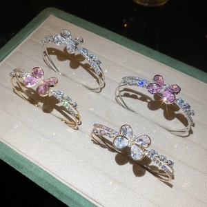 Sparkling butterfly open bangles in gold and silver set on a velvet tray