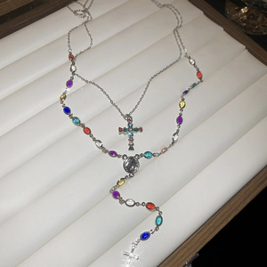 Detail of silver rosary necklace featuring colorful gemstones and a cross pendant in a box