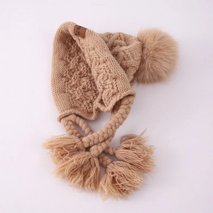 Close-up of knit winter earflap hat featuring thick textures and pom-pom details