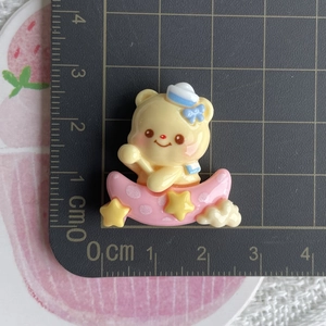 Detail view of yellow bear sailor in pink moon resin charm on a metric scale mat