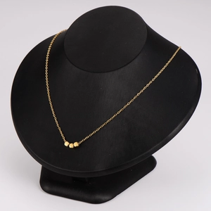 Minimalist gold stainless steel necklace with cube pendants on a black velvet display