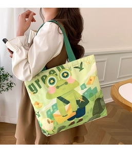 Side view of large green canvas tote bag with frog print worn by model in soft light
