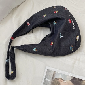 Detailed embroidery of cartoon motifs on dark blue denim tote bag with zipper closure