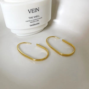 Detail of minimalist gold-plated U-shaped earrings on a sleek white background